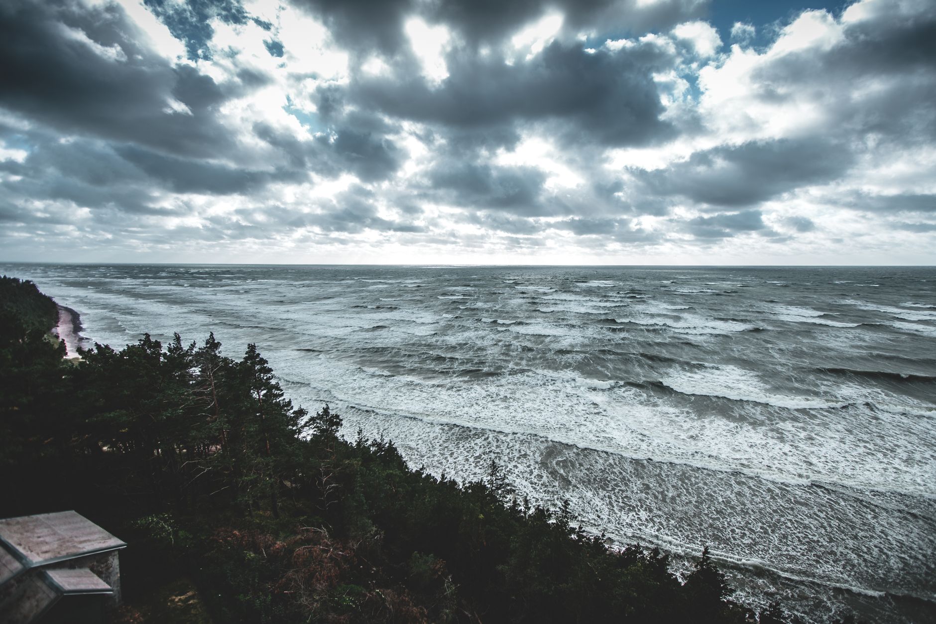 A dramatic view of the Baltic Sea coastline in Latvia with moody skies and waves crashing on the sho