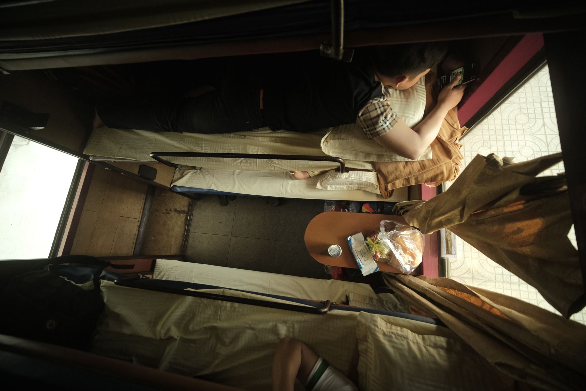 Top view of individuals resting on train bunks with travel essentials.