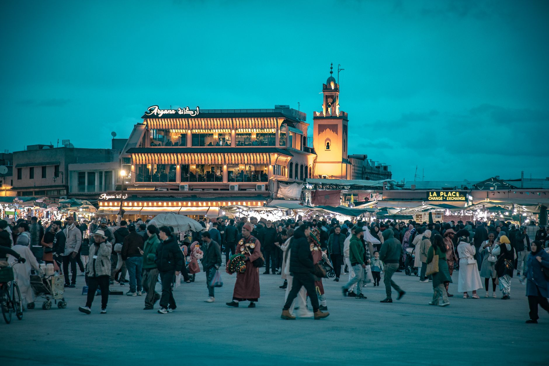 Crowd gathered at iconic Jemaa el-Fnaa square in Marrakesh during dusk, vibrant and lively atmospher