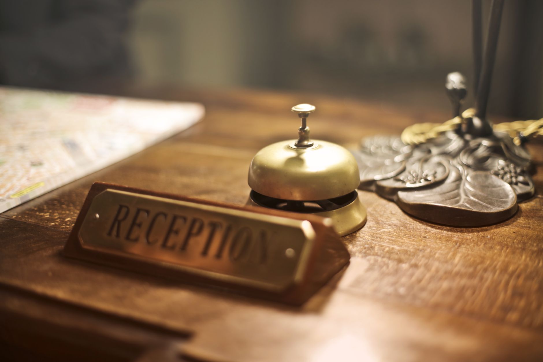 Old fashioned golden service bell and reception sign placed on wooden counter of hotel with retro in