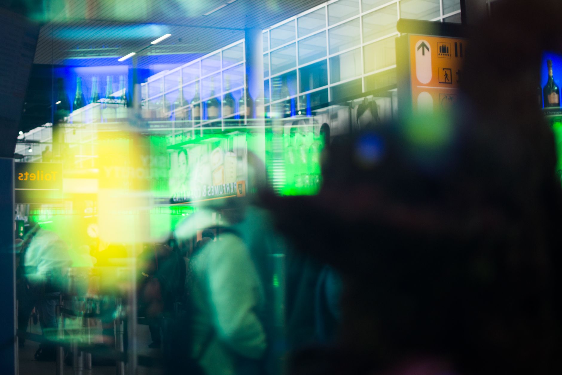 Blurred motion inside a bustling airport terminal with vibrant lights and signs.