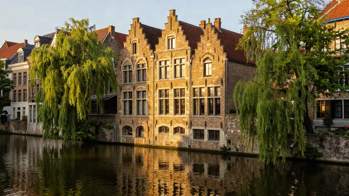 Grachtenhaus mit Spiegelung im Wasser, umgeben von grünen Bäumen