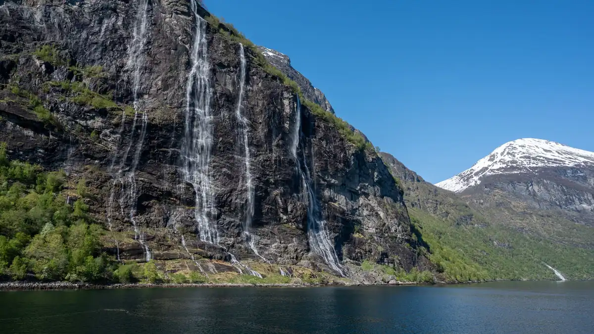 Geirangerfjord mit steilen Felswänden und Wasserfall im Morgenlicht