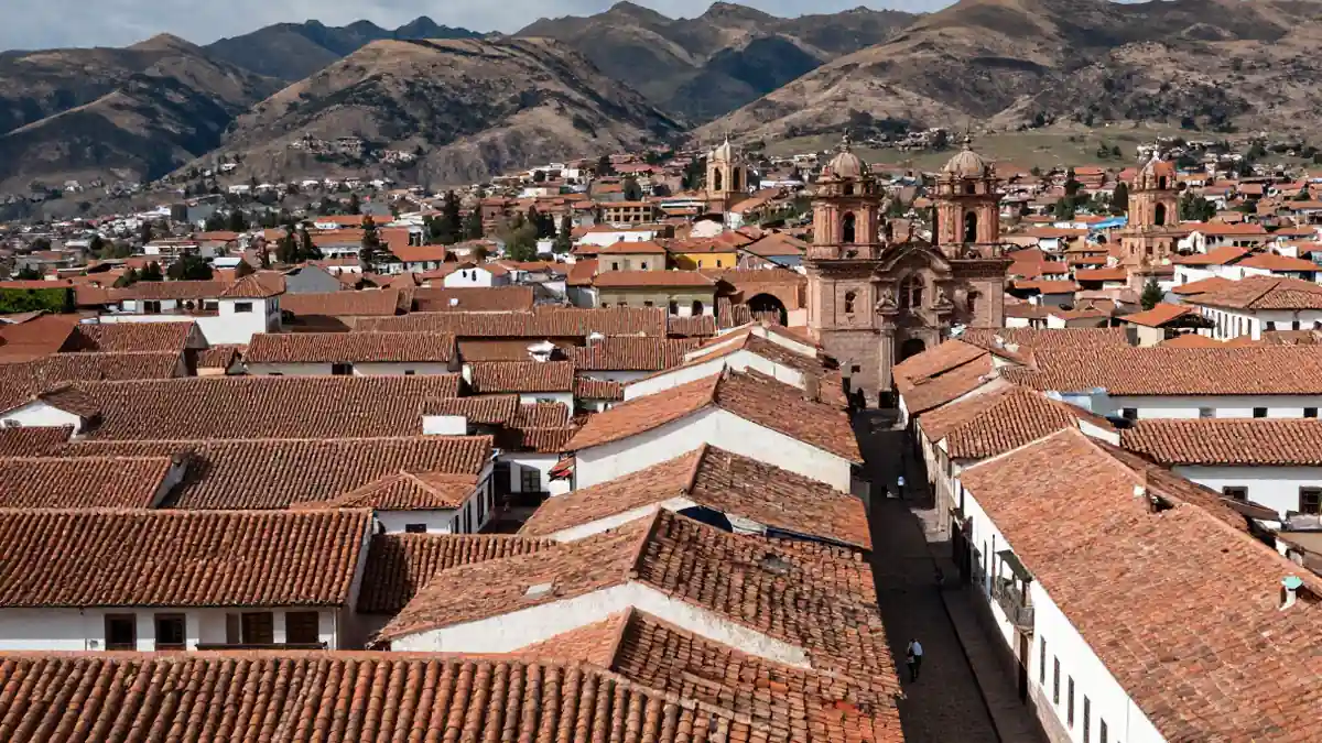 Weitwinkelaufnahme der Altstadt von Cusco mit roten Dächern und Andenkulisse