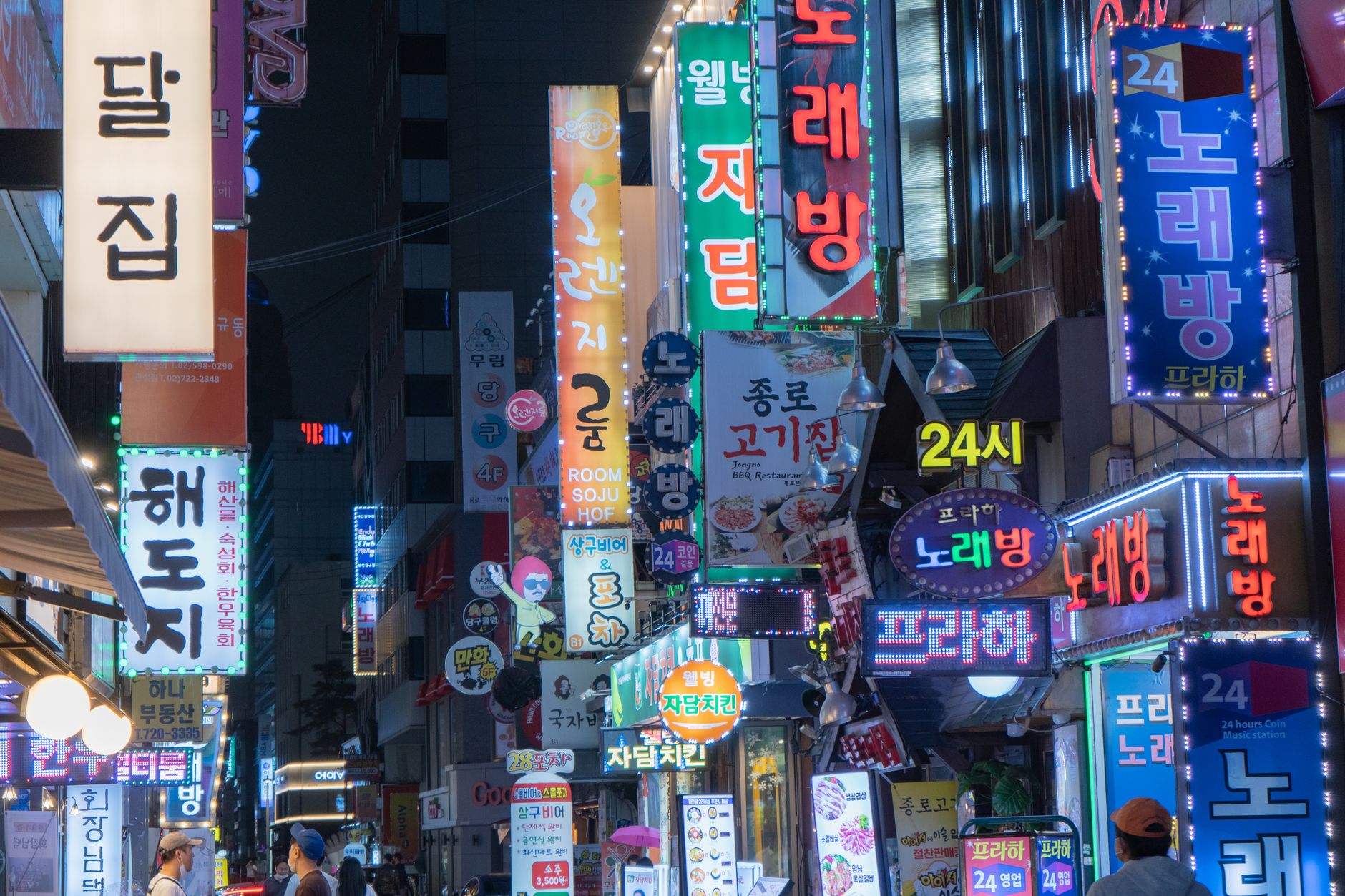 Explore the bustling night scene of Myeongdong with neon signs and vibrant city lights in Seoul, Sou