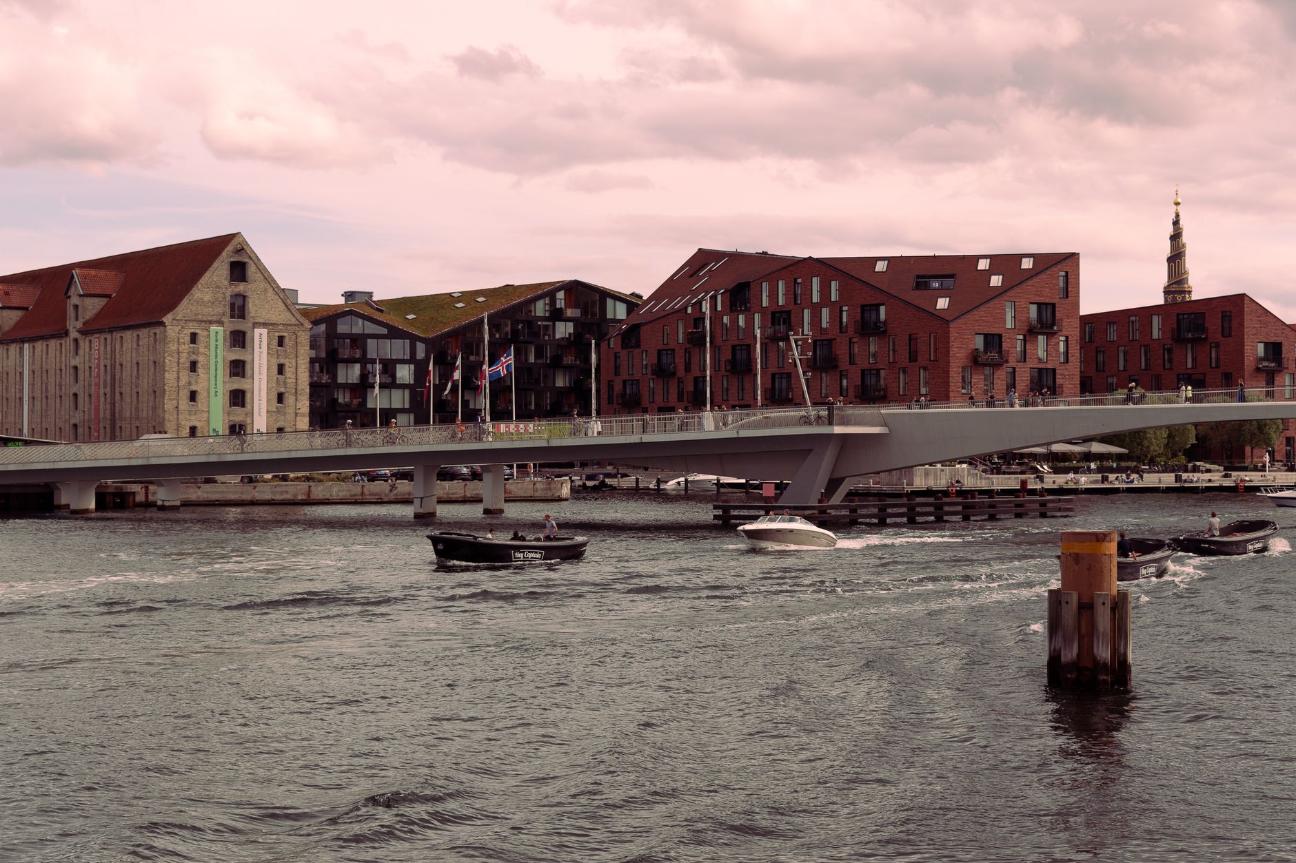 Scenic view of Inderhavnsbroen bridge and waterfront buildings in Copenhagen at dusk.