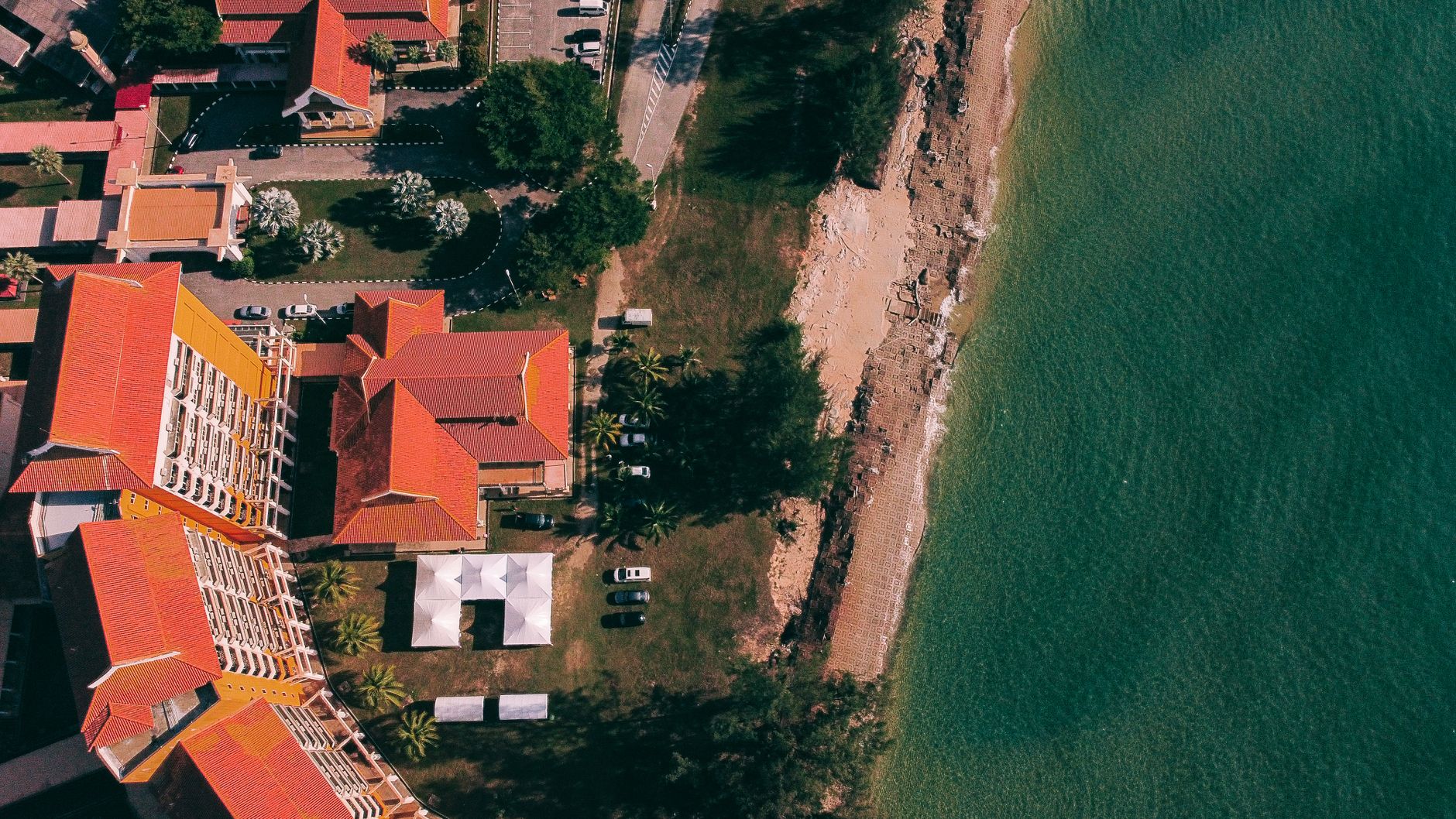 Aerial view of beachfront buildings in Chukai, Malaysia, with red roofs and turquoise waters.
