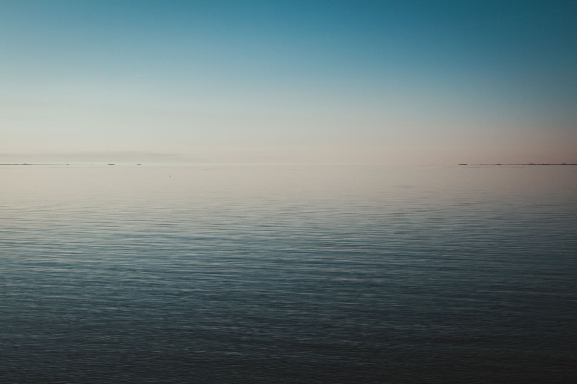 Tranquil seascape view at dawn with calm waters and a clear horizon.