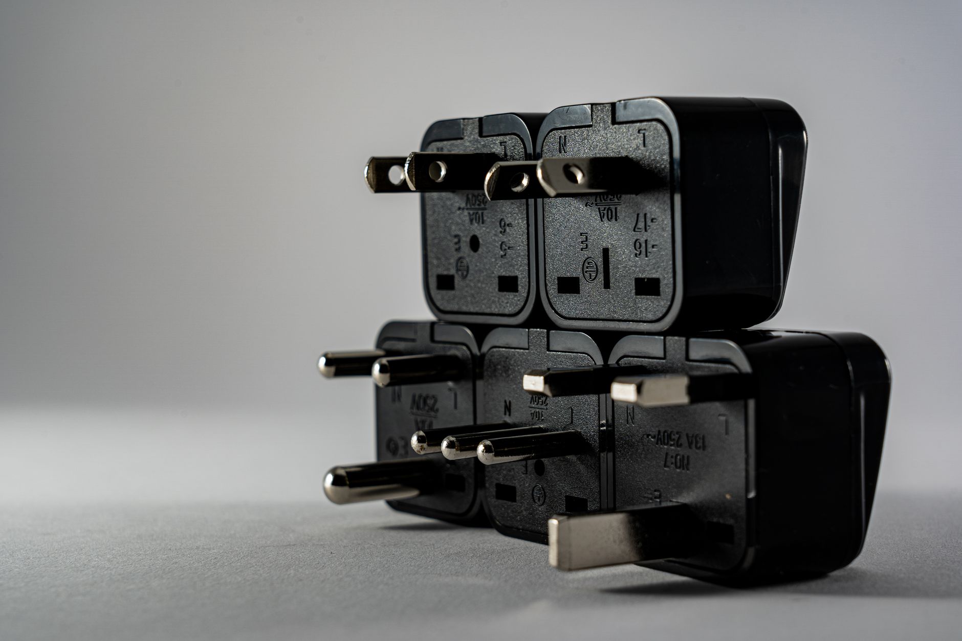 Close-up of black electrical adapters stacked on a gray background.