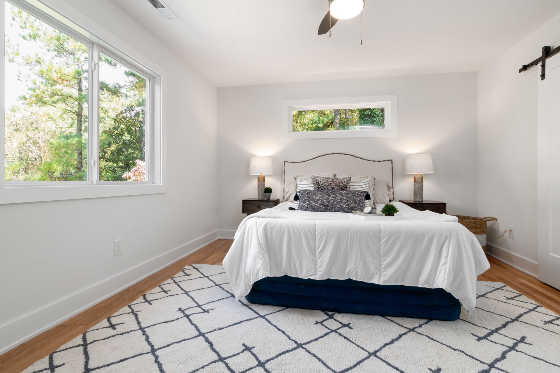 Bright modern bedroom featuring white and blue decor with wooden flooring.